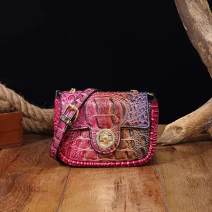Detalle del bolso bandolera con relieve de cocodrilo y un degradado vintage en rosa y rojo