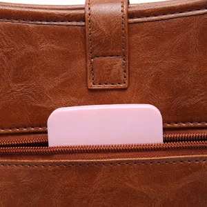 Close-up detail of a vintage brown leather shoulder bag showing the secure zipper pocket.