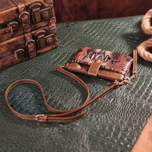 Vintage bohemian snake print small crossbody bag and clutch displayed on a green texture