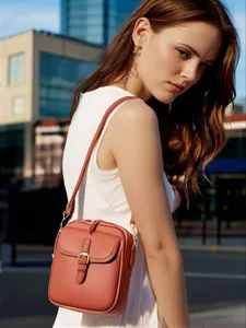 Elegante bolso bandolera de piel sintética marrón terracota lucido por una modelo