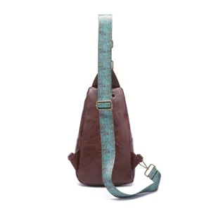 Close-up detail of a vintage brown leather sling bag with bohemian printed turquoise strap