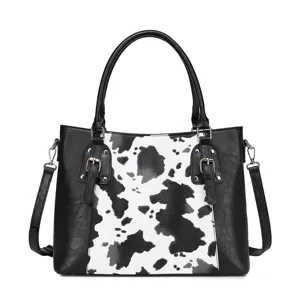 Detalle de la vista frontal de un bolso retro con estampado de vaca y cuero negro.