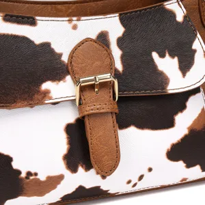 Detalle de cerca de un bolso de piel sintética con estampado de vaca y hebilla de oro