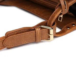 Primer plano de la correa ajustable y la hebilla dorada de un bolso retro de cuero marrón