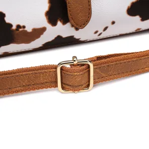 Primer plano de hebilla dorada y correa de cuero marrón del bolso estampado vaca