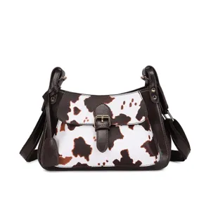 Detalle frontal de bolso bandolera vintage con estampado de vaca y adornos de cuero