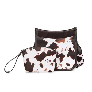 Vista frontal del conjunto de bolsos bohemios con estampado de vaca y estuche