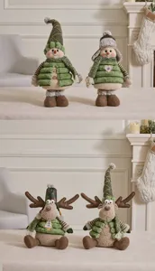 Detail shot of green Christmas plush snowman and reindeer ornaments in cozy home setting.