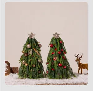 Detailed view of two decorated artificial Norfolk pine tabletop trees in snowy scene.