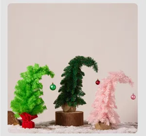 Vue détaillée de trois mini-sapins de Noël colorés au cou tordu sur de la fausse neige.