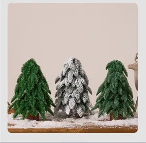 Set of three mini PE artificial Christmas trees with realistic snow on a wooden tabletop