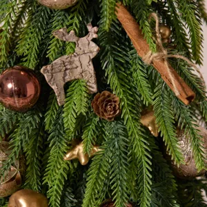 Miniature Norfolk pine Christmas tree with rustic wooden reindeer and cinnamon ornaments