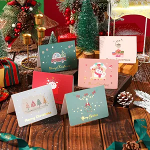 Festive scene of multiple Christmas cards with gold foil lettering and holiday props.