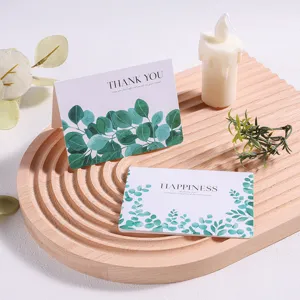 Detailweergave van eenvoudige bosgroene bladwenskaarten op een houten dienblad