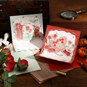 3D-Pop-up-Grußkarten mit Rosen und Schmetterlingen sowie Goldfolie auf Vintage-Schreibtisch