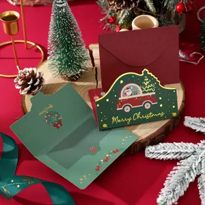 Close-up of green Christmas card with gold foil "Merry Christmas" and red envelope.