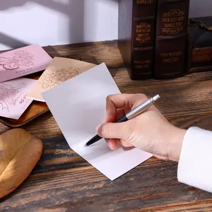 Detail van een hand die op een blanco vintage bloemen wenskaart op een houten tafel schrijft