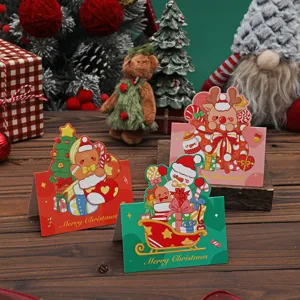 Drei festliche Weihnachtskarten mit Lebkuchen-, Rentier- und Schneemanndesign auf Holz.