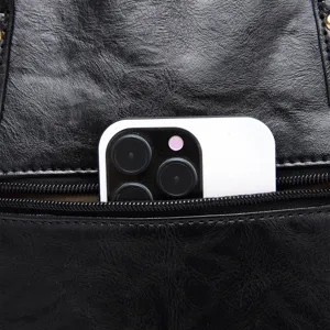 Close-up detail of a back zipper pocket on a black vintage leather tote bag
