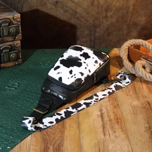Western vintage cow print chest bag with bohemian style and rivet details on wooden table