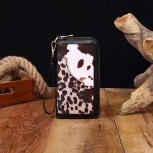 Detailansicht der Damenclutch mit Leoparden- und Kuhmuster im Boho-Stil auf Holz