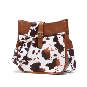 Western vintage crossbody bag featuring brown and white cow print and wide strap