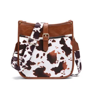 Vintage bohemian crossbody bag with chic cow print and brown faux leather detail.