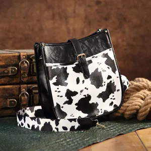 Lifestyle view of vintage western cow print crossbody bag featured with antique trunks.