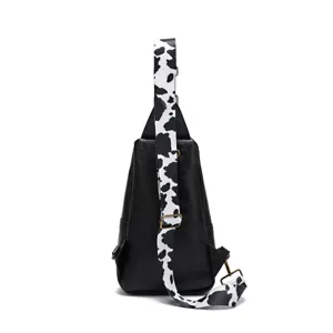 Detail view of black sling bag with trendy cow print adjustable shoulder strap