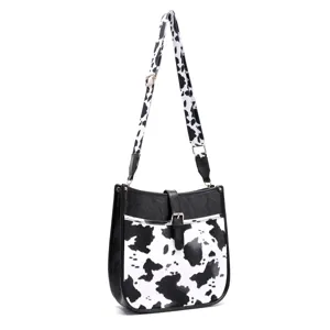 Detail view of a western boho style crossbody bag with black and white cow print.