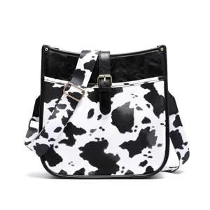 Bohemian western style crossbody bag featuring black and white cow print and wide strap