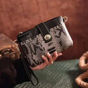 Detailed close-up view of a vintage snakeskin print crossbody clutch bag held by a hand