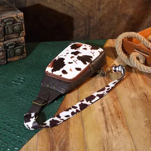 Macro detail of a vintage Western cow print sling bag featuring retro brass studs