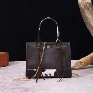 Detail view of a vintage brown mini tote bag with cow print panel and gold chain.
