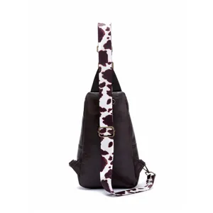 Detail view of a vintage western sling bag featuring a stylish brown cow print strap