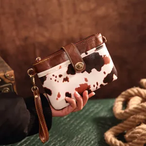 Vintage western cow print small crossbody bag bohemian clutch being held in hand