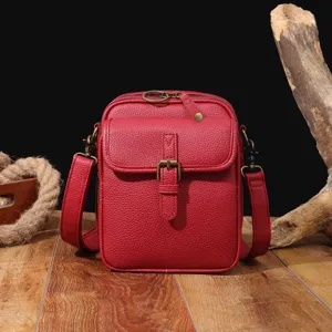 Bolso bandolera vintage de cuero granulado rojo con hebilla sobre madera rústica
