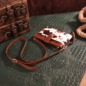 Detail of the cow print texture and brown faux leather trim on the small crossbody bag