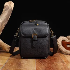 Vista frontal de un bolso mensajero de cuero granulado negro con hebilla vintage