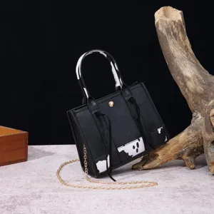 Western retro printed handbag with cow pattern and gold chain strap in rustic setting
