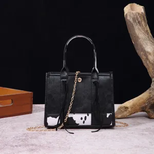 Detailed view of bohemian mini handbag featuring vintage cow print and long tassels
