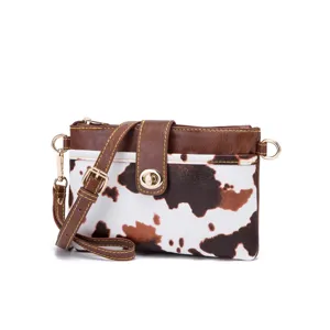Detail view of the vintage cow print pattern and gold turn-lock on the leather bag.