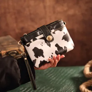 Close-up detail of a vintage cow print crossbody clutch bag with gold hardware lock