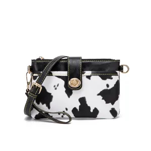 Western style cow print crossbody bag with gold-tone hardware and black faux leather trim.