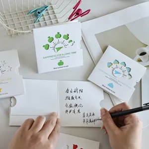 Close-up of hand writing warm wishes inside a minimalist hollowed-out greeting card
