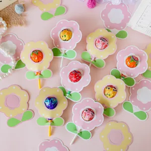 Detail of flower-shaped lollipop cards in pink and yellow for gift decoration.