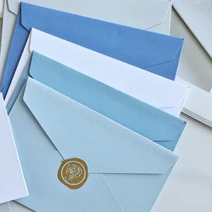 Primo piano di buste minimaliste blu e bianche con un sigillo in cera a rosa dorata.