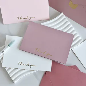 Primo piano di eleganti biglietti di ringraziamento in rosa, bianco e malva dorati