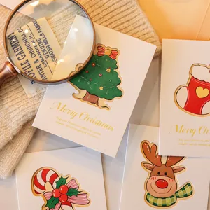 Close-up of hollowed-out Christmas greeting cards with festive tree and reindeer motifs