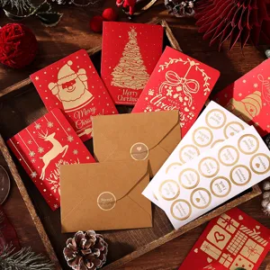 Nahaufnahme festlicher roter Weihnachtskarten mit Goldfolie und Kraftpapierumschlägen